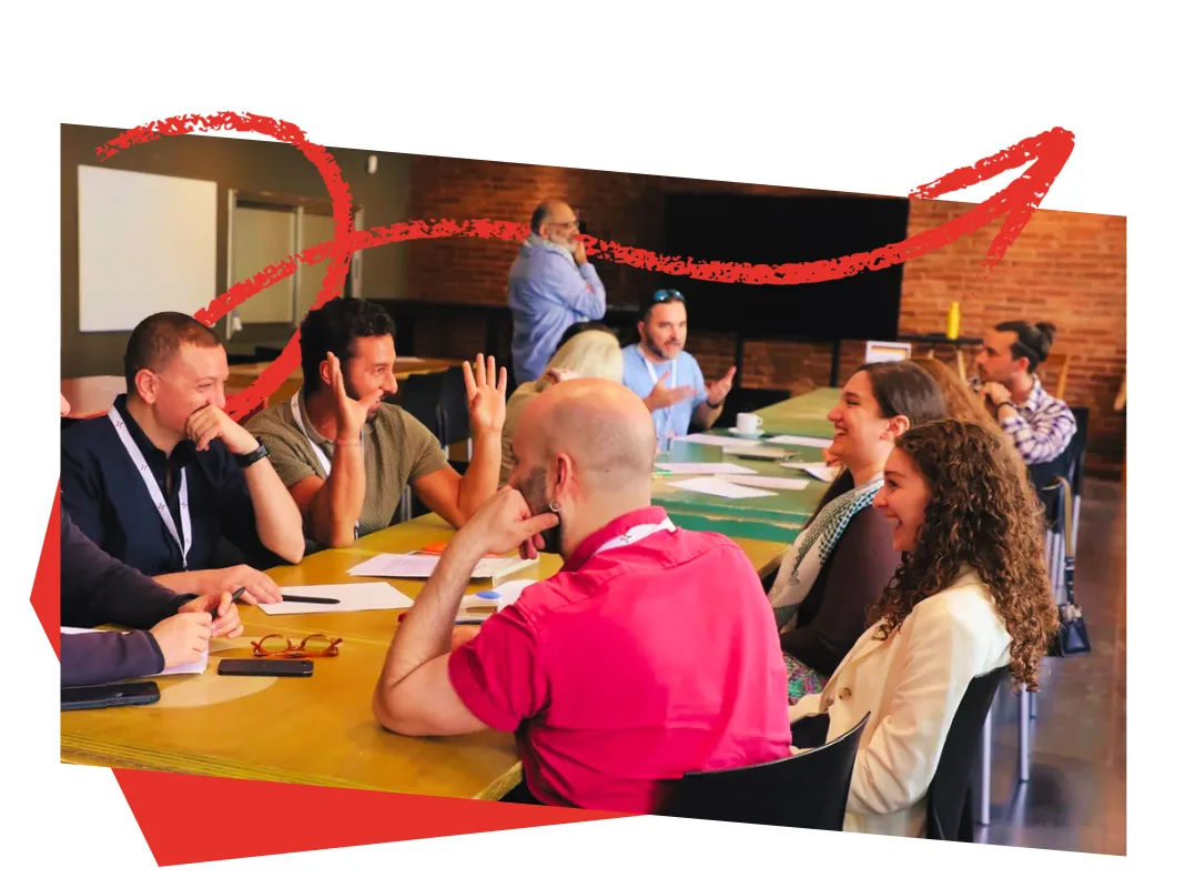 Hackathon participants laughing and debating ideas around a long workshop table